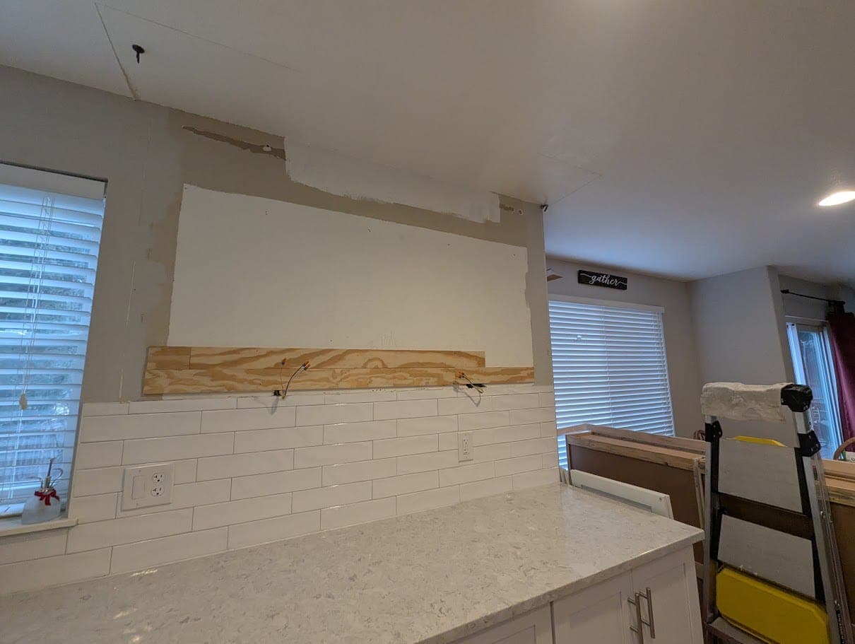 Damaged kitchen ceiling drywall opened to trace a toilet leak from the bathroom above.